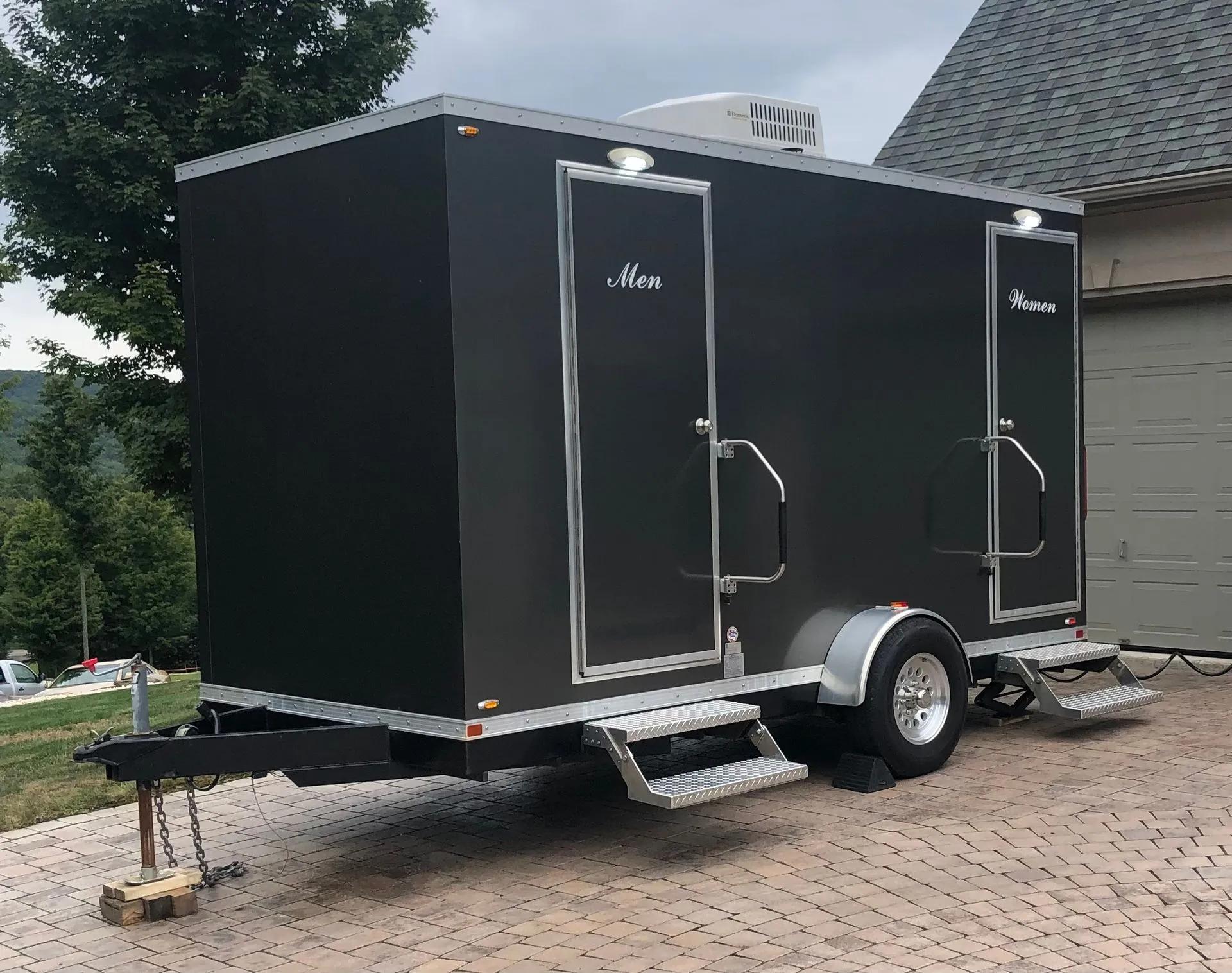 Black, small portable restroom trailer showing men's and women's room.